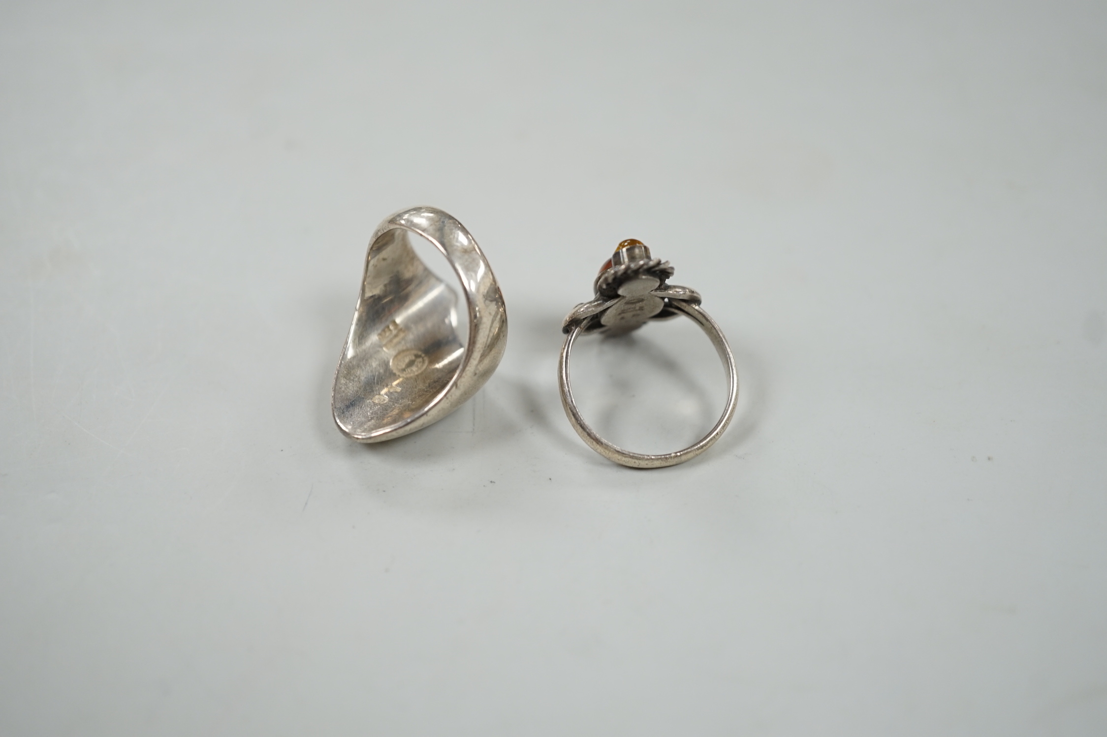 A Georg Jensen sterling ring, design no. 91, size Q and a Georg Jensen? sterling and three stone amber set ring, design no. 15.